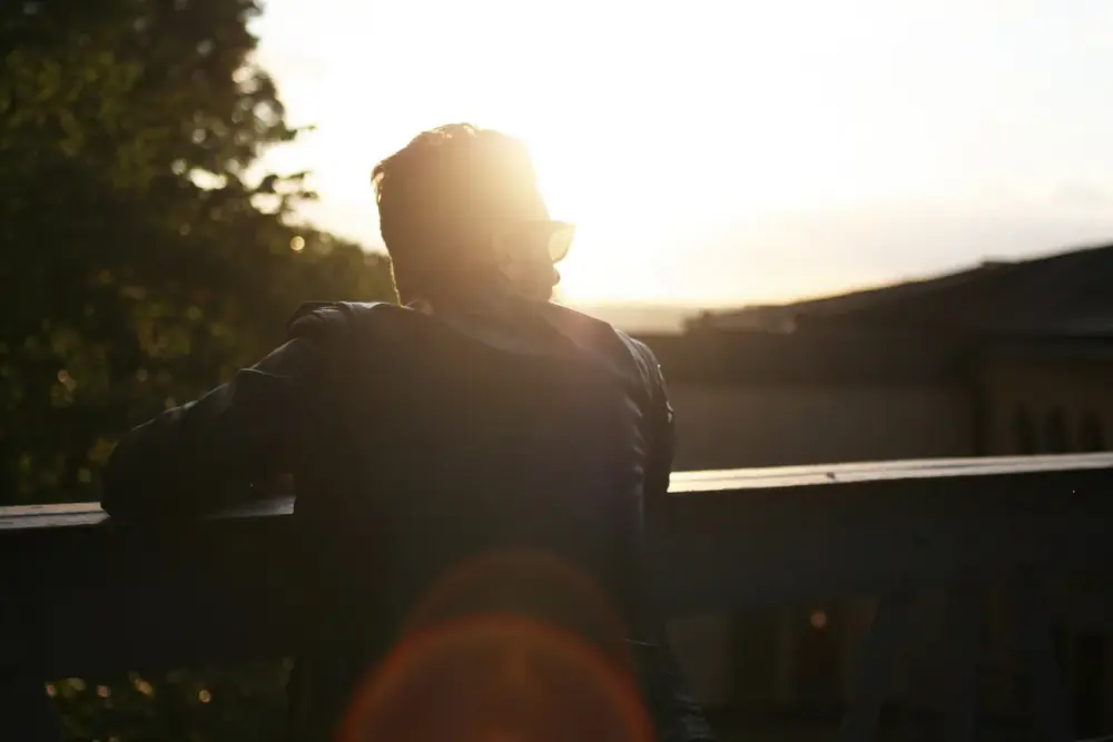 A man in a dark jacket silhouetted against early morning sun