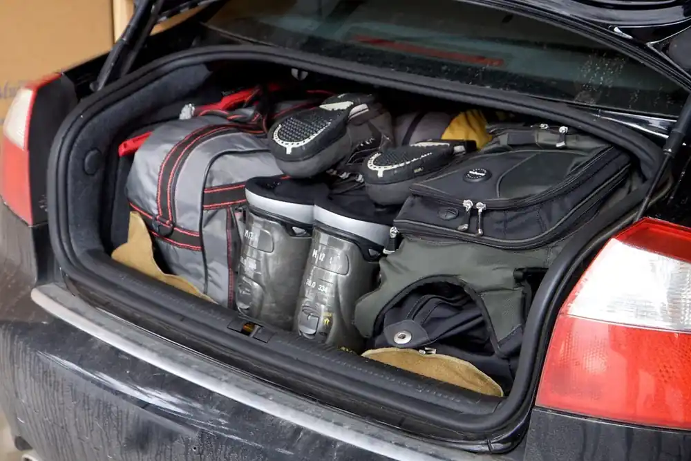 An open car trunk packed with soft bags and boots