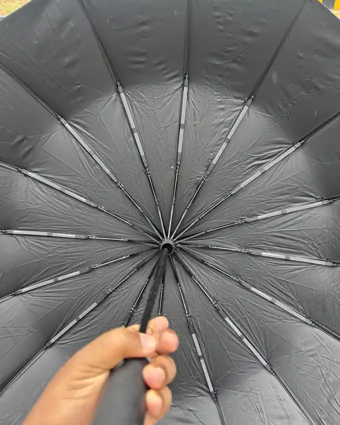 Looking up into a black umbrella canopy, its ribs fanning out from the shaft
